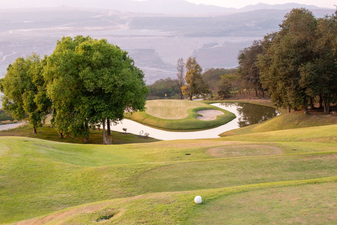 Stunning golf course landscape with a pond, perfect for a summer day of golfing.